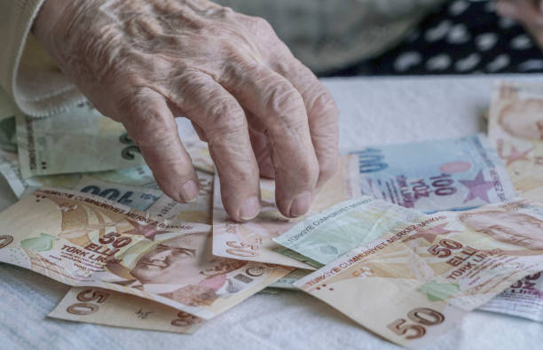 Closeup of wrinkled hands counting turkish lira banknotes stock photo
