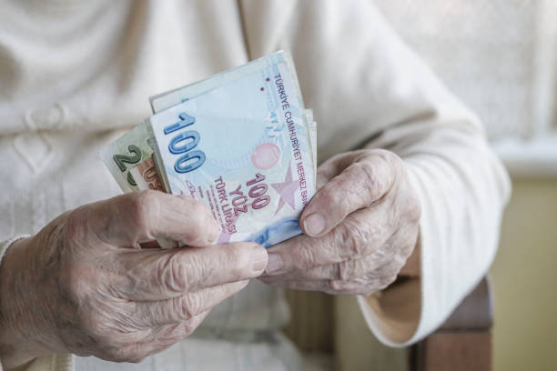 Closeup of wrinkled hands holding turkish lira banknotes stock photo