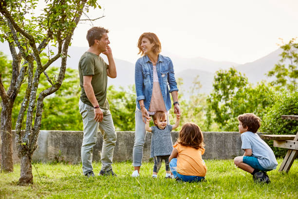 happy parents talking while kids playing on field - little girls pre adolescent child standing isolated zdjęcia i obrazy z banku zdjęć