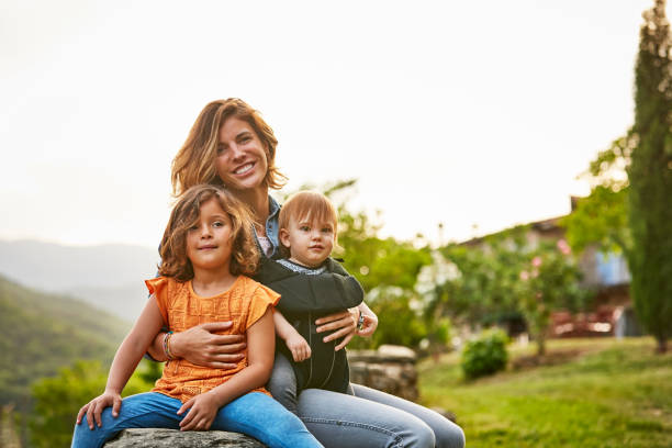 portrait du sourire des enfants porteurs de mère à yard - famille avec deux enfants photos et images de collection