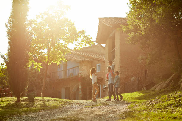 Full length of family standing against houses Full length of family standing on pathway against houses. Parents and children enjoying on sunny day. They are in casuals. mid distance stock pictures, royalty-free photos & images