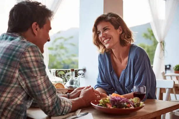 Smiling couple talking at table. Happy man and woman are in casuals. They are spending leisure time in restaurant.