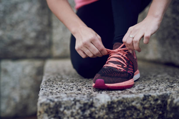 Get ready for a great run Shot of an unidentifiable young woman tying her shoelace before a run in the city lace fastener photos stock pictures, royalty-free photos & images
