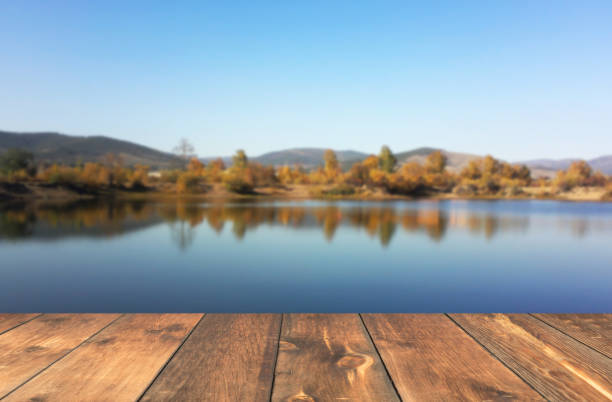 istock empty wooden table blured lake landscape 658998882