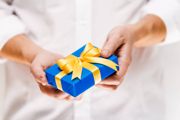 istock Male hands holding a blue gift box with ribbon. 659018710