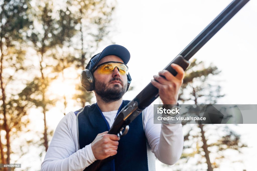 Clay target shooter in sunset Professional trap shooter shooting clay targets. Shotgun Stock Photo