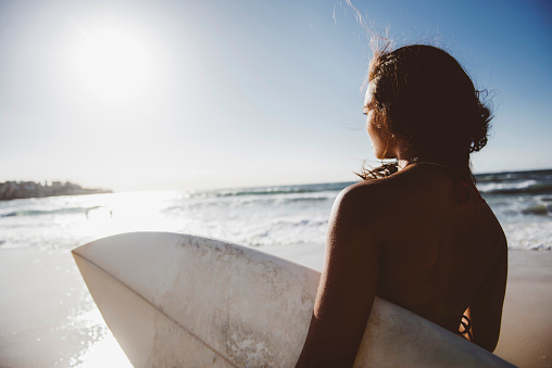 Girl preparing to surf at Bondi beach.