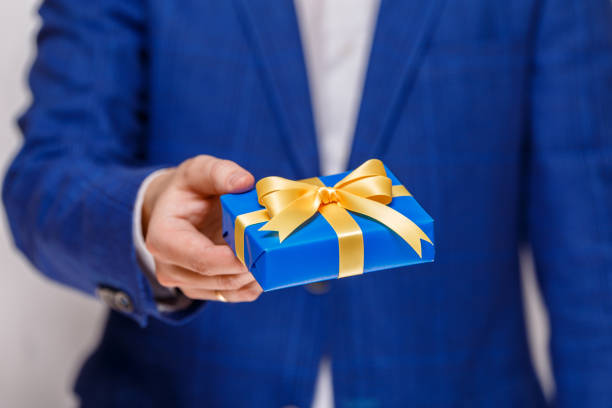 istock Male hand holding a blue gift box with ribbon. 659056426