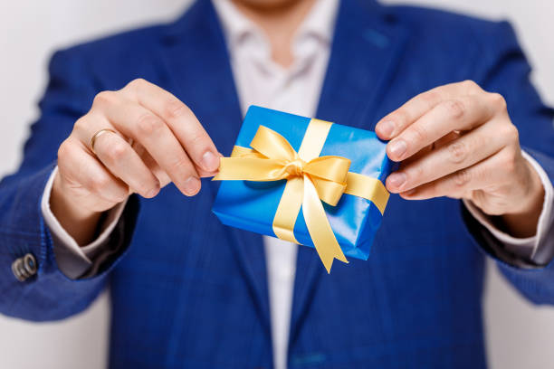 istock Male hands holding a blue gift box with ribbon. 659056700
