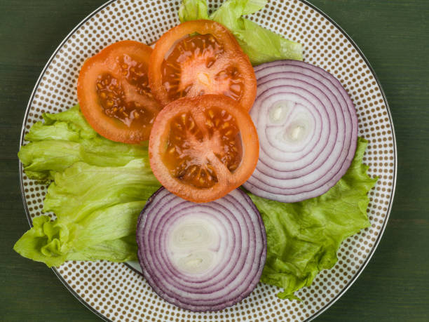 Fresh Garden Salad Tomato Onion and Lettuce Against a Green Background