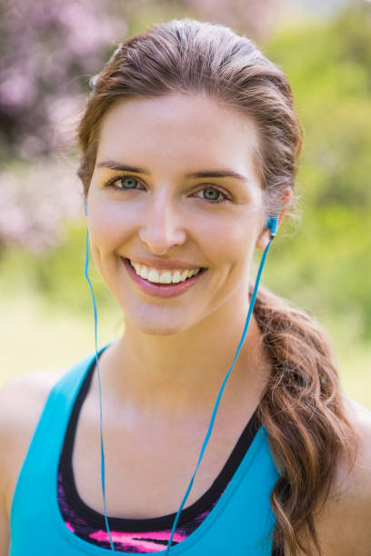 smiling woman wearing earphones - running jogging footpath cross country running imagens e fotografias de stock