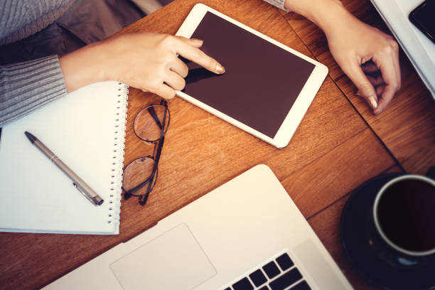 istock Technology concept: girl using a tablet with blank screen for copy space , hardwood desktop and stationery on background 659082288