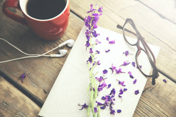 istock flowers and glasses on notebook and cup of coffee and headset on table 659082470