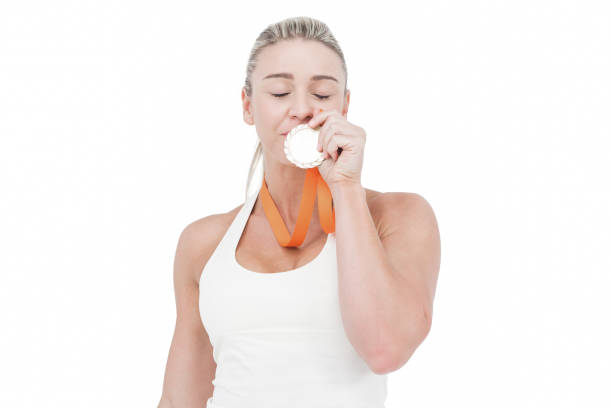 happy female athlete kissing medal - effort gold indoors studio shot imagens e fotografias de stock
