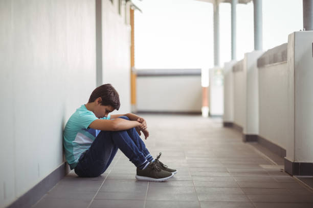 istock Sad schoolboy sitting in corridor 659095086