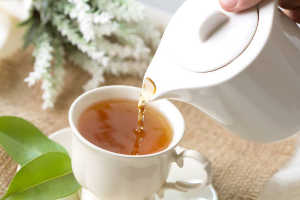 istock pouring hot black tea in a white tea cup 659119530