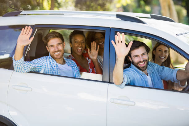 istock Group of friends waving hands from car 659150788
