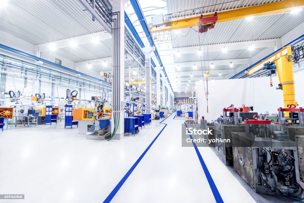 Modern factory & aisle Horizontal image of huge new modern factory with robots and machines producing industrial plastic pieces and equipment. Wide angle view of futuristic machines and long aisle. Factory Stock Photo