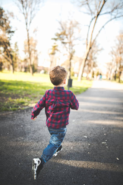 Running in the sun Small boy running in the park on a sunny day runaway stock pictures, royalty-free photos & images