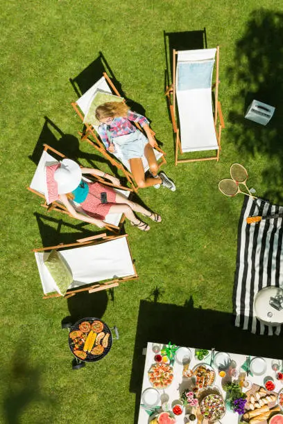 Top view of women lying on deckchairs in garden