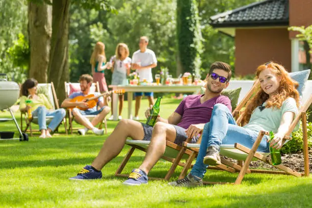 Young couple sitting on deckchairs during garden party