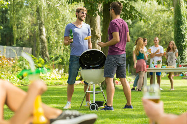 dos hombres de pie junto a la parrilla - deck chair summer grass outdoor chair fotografías e imágenes de stock