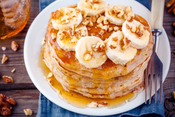 istock Oat pancakes with banana, walnuts and maple syrup closeup 659192528