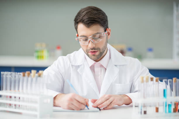 istock portrait of focused man scientist in protective glasses writing in notepad 659198716