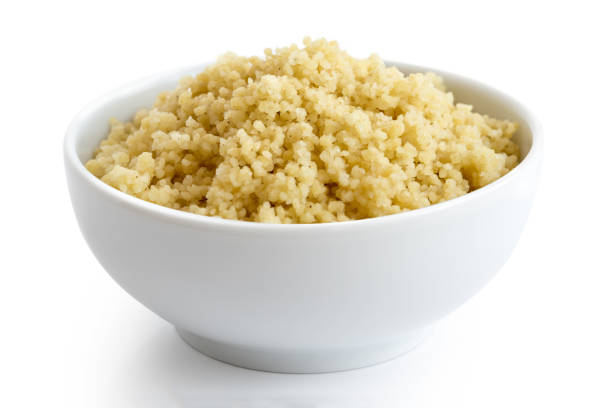 Cooked couscous in white ceramic bowl isolated on white.