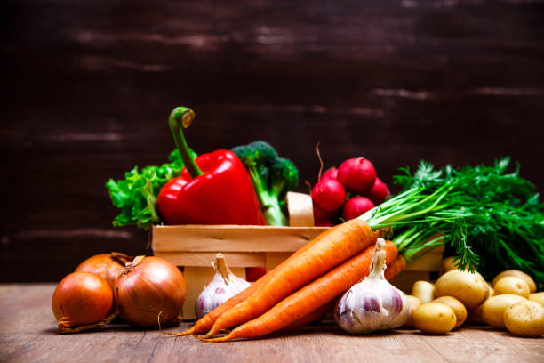 Vegetables. Potatoes, carrot and red pepper. Lettuce salad, garlic and brocoli. Onion and radish. Wooden basket on rustic table.