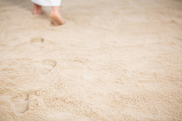 Jesus leaving footprints in sand Jesus Christ walking and leaving footrpints in sand walking with god stock pictures, royalty-free photos & images