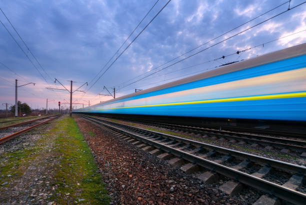 istock High speed blue passenger train in motion on railroad at sunset. Blurred commuter train. Railway station against cloudy sky. Railroad travel, railway tourism. Rural industrial landscape. Concept 659229184