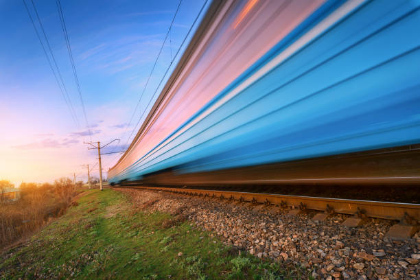 istock High speed blue passenger train in motion on railroad at sunset. Blurred commuter train. Railway station against colorful sky. Railroad travel, railway tourism. Rural industrial landscape. Concept 659229192