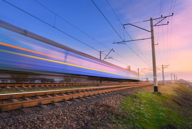 High speed passenger train in motion on railroad at sunset. Blurred commuter train. Railway station against colorful blue sky. Railroad travel, railway tourism. Rural industrial landscape. Concept tren de pasajeros de alta velocidad en movimiento en el ferrocarril al atardecer. tren de cercanías borroso. estación de ferrocarril contra el colorido cielo azul. viajes ferroviarios, turismo ferroviario. paisaje industrial rural. concepto