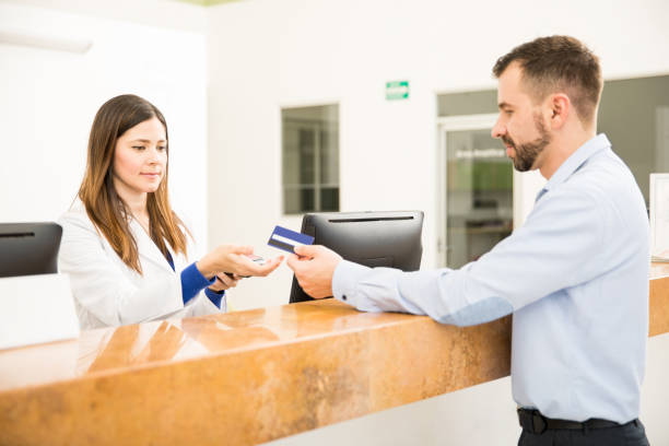 recepcionista que realiza el pago con tarjeta de crédito - healthcare and medicine receptionist paying credit card fotografías e imágenes de stock