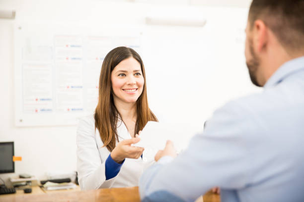 Receptionist handing results to patient Pretty receptionist handing over lab test results to a patient with a smile technology office equipment laboratory stock pictures, royalty-free photos & images