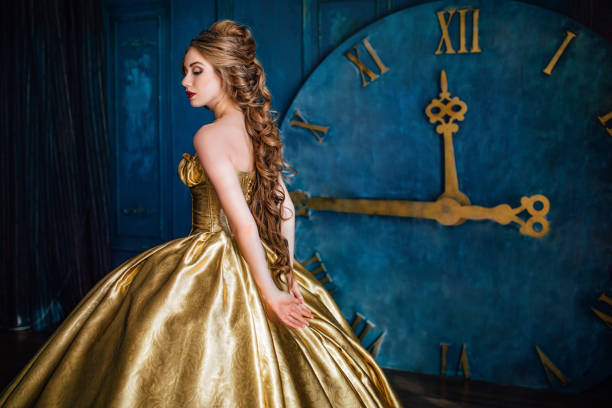 Beautiful woman in a ball gown Beautiful woman in a golden ball gown in the great blue interior evening ball stock pictures, royalty-free photos & images