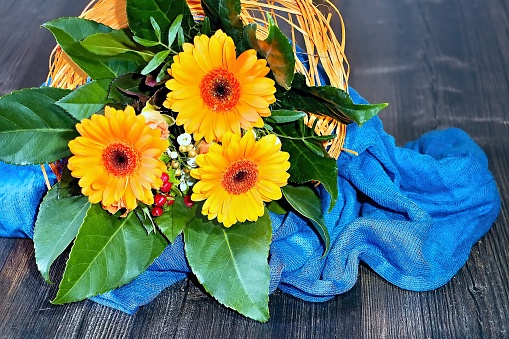 Orange gerberas in a beautiful small bouquet to light blue tablecloth.