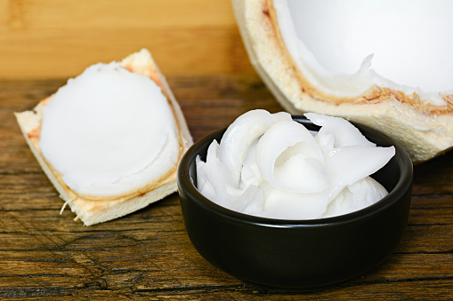 young coconut meat sliced in black bowl on wooden table