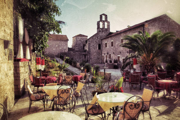 Empty coffee terrace with tables and chairs in old town of Budva on sunny day at sunset, Montenegro. Filtered image, vintage effect applied. Grunge