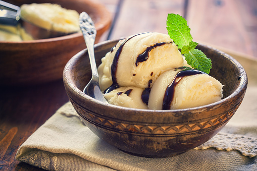 Homemade vanilla ice cream with mint served in the old wooden bowl