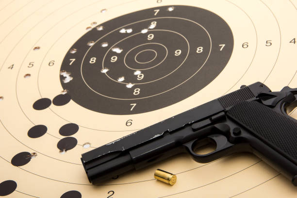 istock 9 mm black pistol over paper target with holes and cartridge shell 659315514