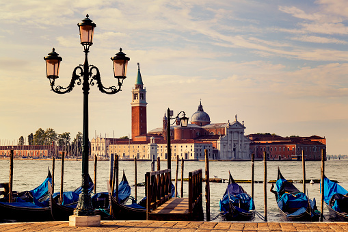 Gondolas in Venice view on San Giorgio Maggiore church from San Marco square in Italy. Beautiful traditional ornate gondola boats navigating or mooring in the narrow canals of Venice, in Italy. Travel destination background with copy space.