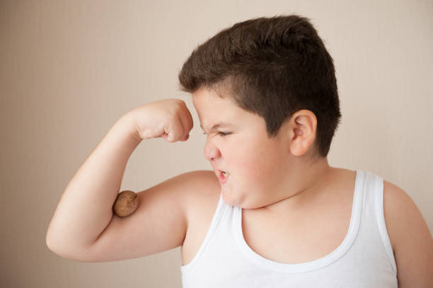 istock fat boy in a vest holding a nut on the hand 659365636