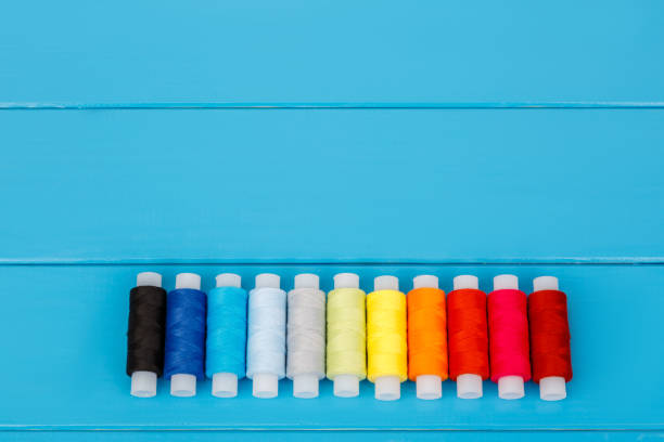 istock Row of threads laying on blue wooden background 659403844