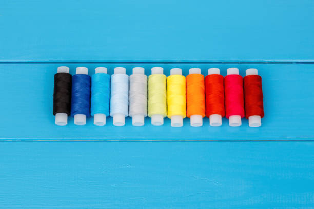 istock Row of threads laying on blue wooden background 659406064