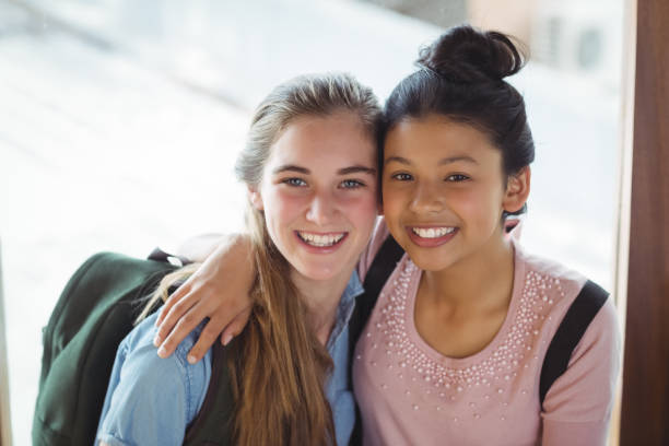 Portrait of schoolgirls embracing each other in corridor Portrait of schoolgirls embracing each other in corridor at school cute 15 year old girls stock pictures, royalty-free photos & images