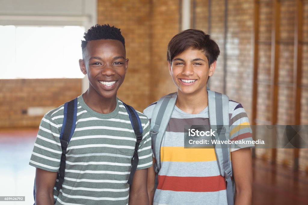 Portrait of happy schoolboys with schoolbag standing in campus Portrait of happy schoolboys with schoolbag standing in campus at school Teenage Boys Stock Photo