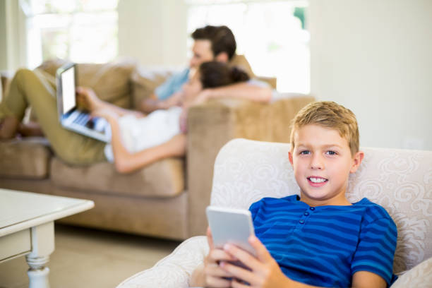 istock Portrait of boy sitting on sofa and using mobile phone 659468686
