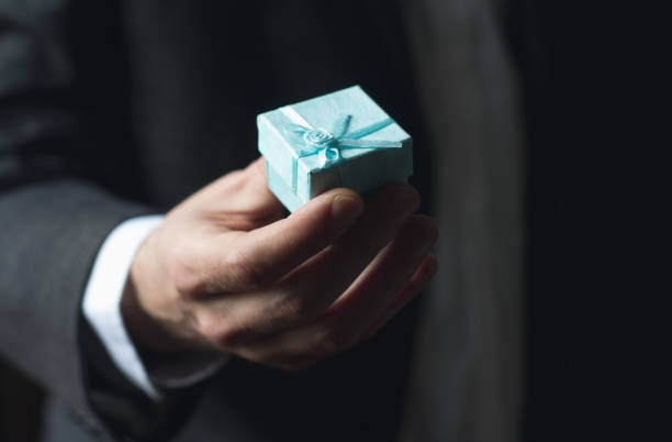 istock Man offering gift with blue ribbon 659493926